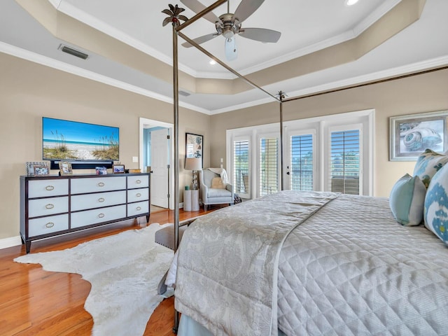 bedroom featuring ceiling fan, wood-type flooring, ornamental molding, and a raised ceiling