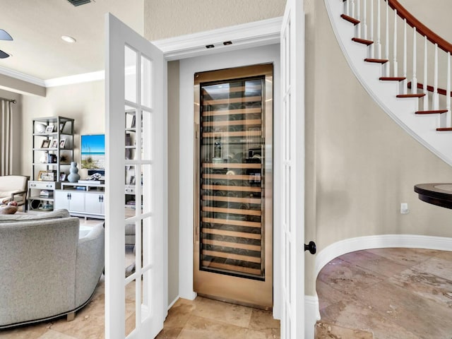 wine room featuring french doors, beverage cooler, and ornamental molding