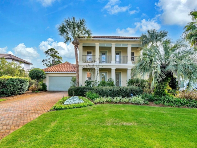 view of front of property with a front yard, a garage, and a balcony