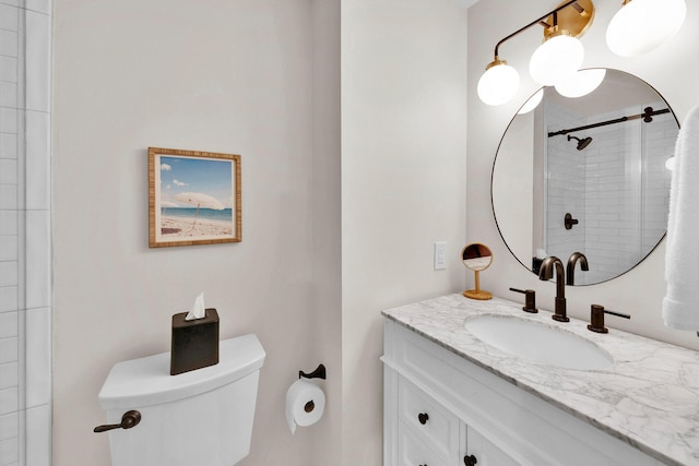 bathroom featuring a tile shower, vanity, and toilet