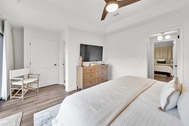 bedroom featuring ceiling fan, hardwood / wood-style flooring, and a tray ceiling