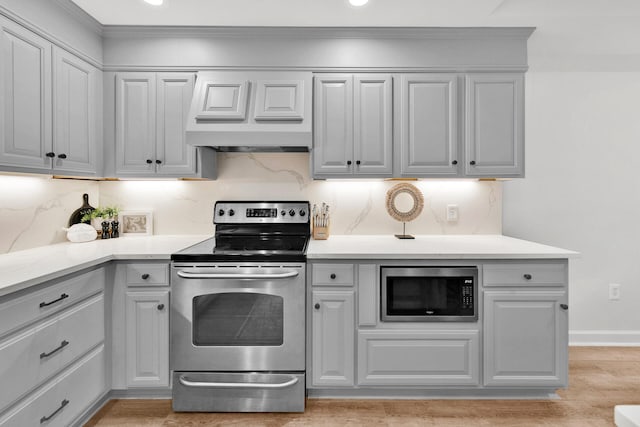 kitchen featuring stainless steel range with electric cooktop, built in microwave, custom range hood, backsplash, and gray cabinetry