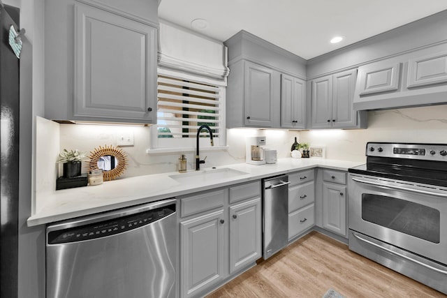 kitchen featuring sink, stainless steel appliances, light hardwood / wood-style floors, and gray cabinets