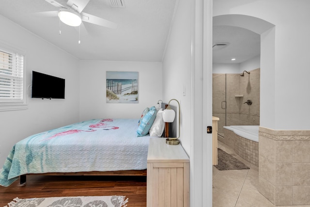 bedroom with light tile patterned floors, ensuite bathroom, and ceiling fan