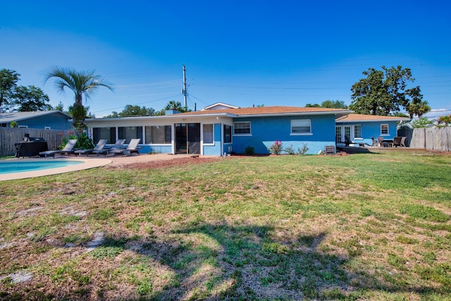 rear view of property featuring a sunroom, a fenced in pool, a patio, and a lawn