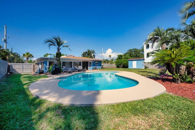 view of swimming pool featuring a yard and a storage shed