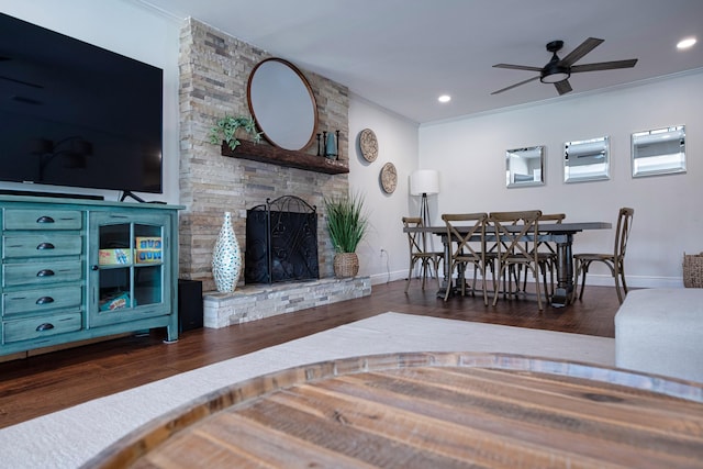 living room with ceiling fan, dark hardwood / wood-style floors, crown molding, and a fireplace