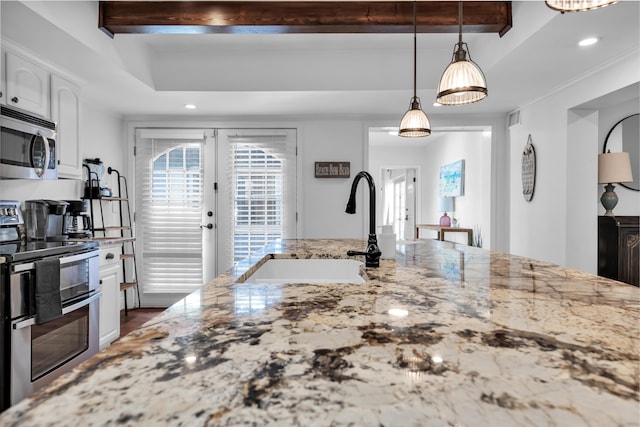 kitchen featuring light stone countertops, stainless steel appliances, sink, decorative light fixtures, and white cabinets