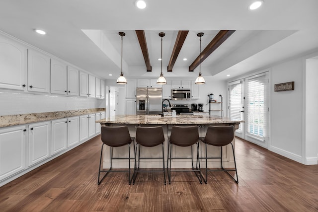 kitchen featuring pendant lighting, white cabinets, an island with sink, tasteful backsplash, and stainless steel appliances