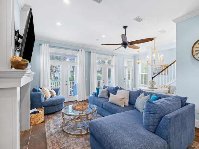 tiled living room with french doors, crown molding, and ceiling fan with notable chandelier