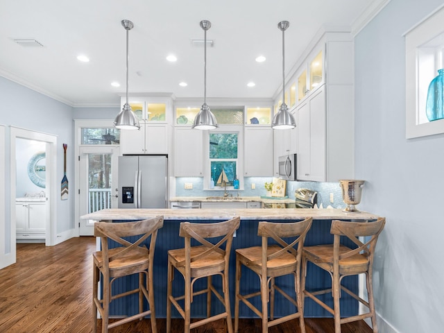 kitchen featuring appliances with stainless steel finishes, pendant lighting, white cabinetry, sink, and dark hardwood / wood-style flooring