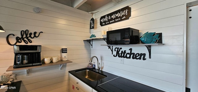 kitchen featuring wooden walls and sink