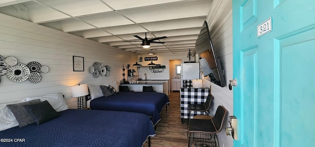 bedroom featuring sink, dark hardwood / wood-style flooring, wood walls, and a drop ceiling