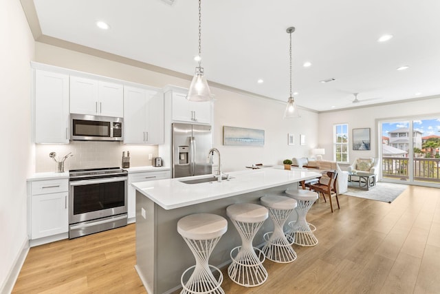 kitchen with pendant lighting, ceiling fan, an island with sink, appliances with stainless steel finishes, and white cabinetry