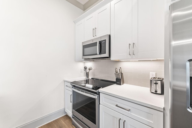 kitchen featuring appliances with stainless steel finishes, backsplash, light hardwood / wood-style floors, and white cabinetry