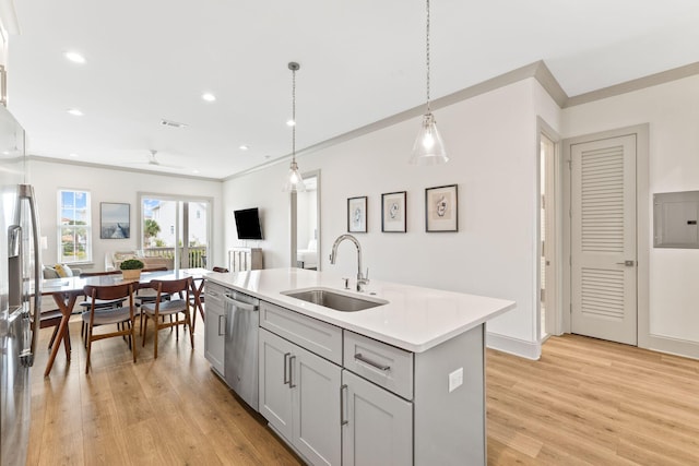 kitchen with appliances with stainless steel finishes, sink, pendant lighting, gray cabinets, and an island with sink