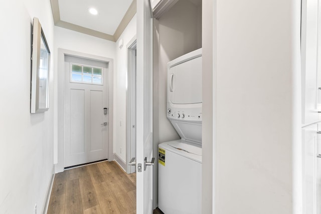 clothes washing area featuring stacked washing maching and dryer and light hardwood / wood-style floors