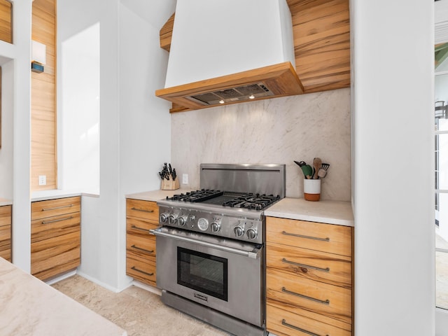 kitchen with high end stainless steel range oven, custom range hood, and backsplash