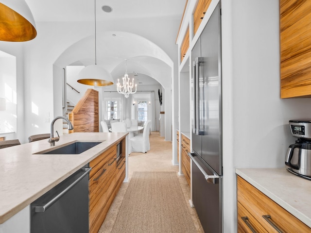 kitchen featuring pendant lighting, sink, lofted ceiling, appliances with stainless steel finishes, and an inviting chandelier