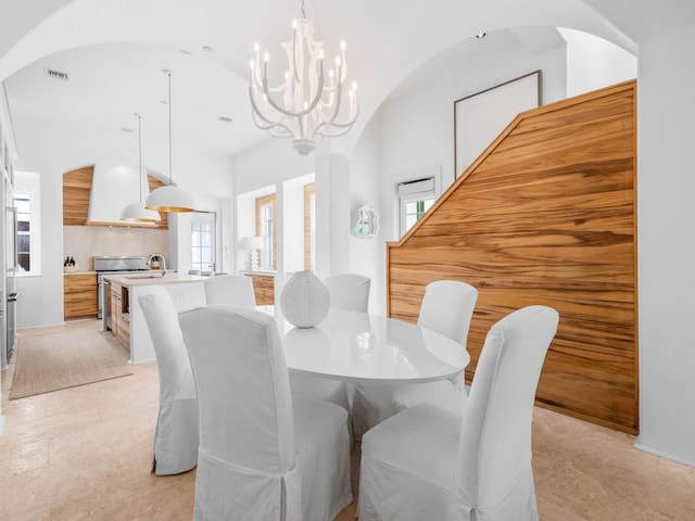 dining space with lofted ceiling, sink, and a chandelier