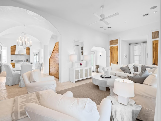 living room featuring lofted ceiling, ceiling fan with notable chandelier, and light carpet