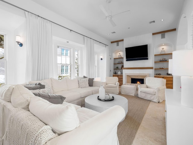 living room featuring built in features and ceiling fan