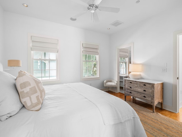 bedroom featuring ceiling fan, multiple windows, and light wood-type flooring