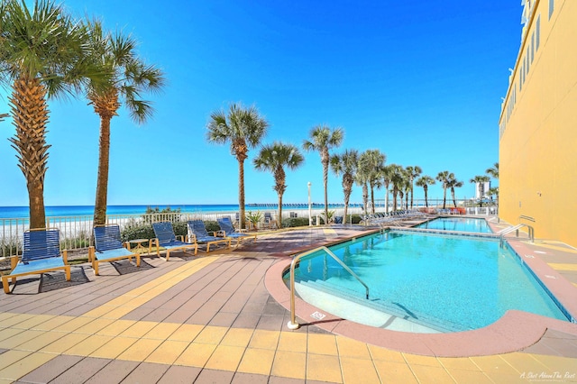 view of pool featuring a water view and a patio