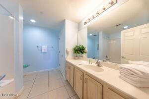 bathroom with tile patterned flooring, vanity, and a shower