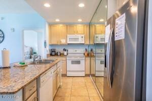 kitchen featuring light stone countertops, sink, white appliances, light brown cabinetry, and light tile patterned floors