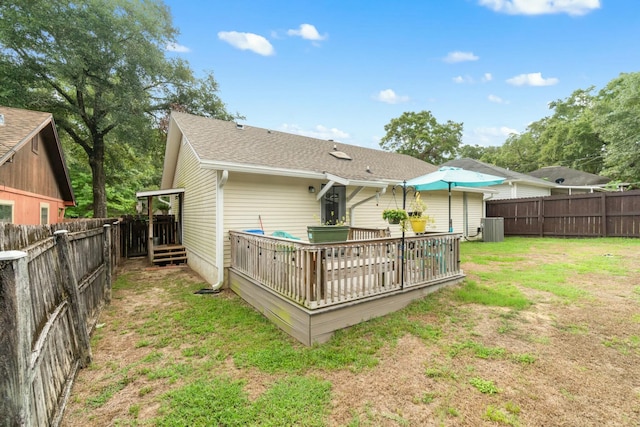 rear view of house featuring a lawn, central air condition unit, and a deck