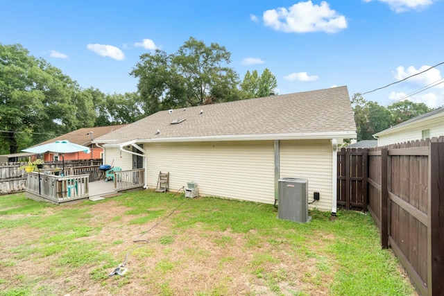 rear view of property with a deck, a lawn, and central air condition unit