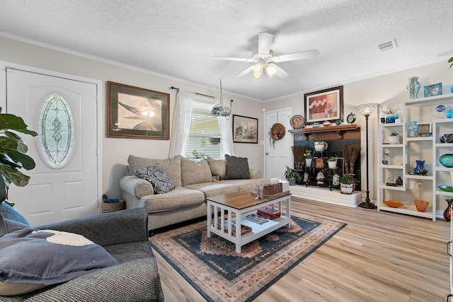 living room featuring wood-type flooring, a textured ceiling, ceiling fan, and crown molding