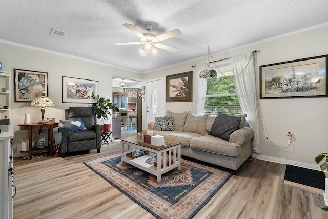 living room featuring ceiling fan, wood-type flooring, a textured ceiling, and ornamental molding