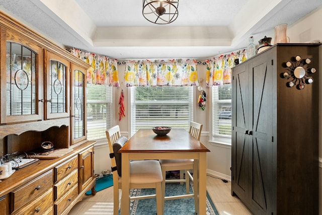 dining space featuring a tray ceiling and light tile patterned floors