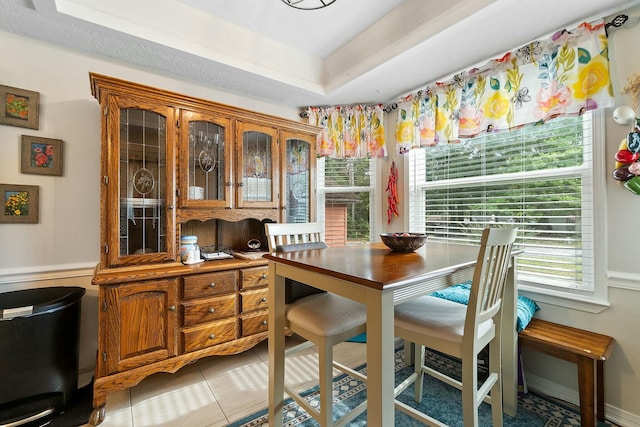 tiled dining room with a raised ceiling