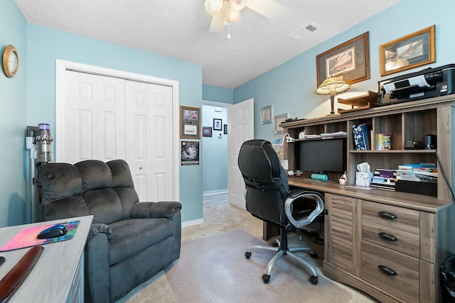 home office featuring ceiling fan, light colored carpet, and a textured ceiling