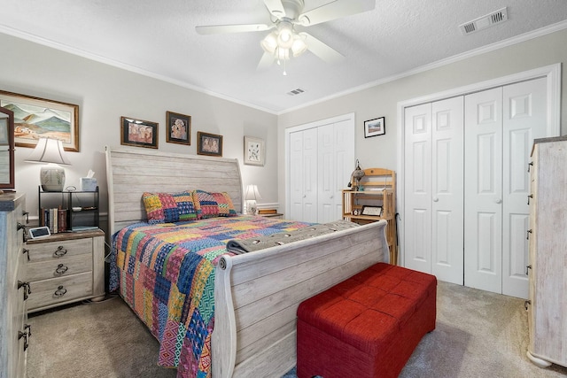 bedroom featuring carpet, a textured ceiling, ceiling fan, crown molding, and multiple closets