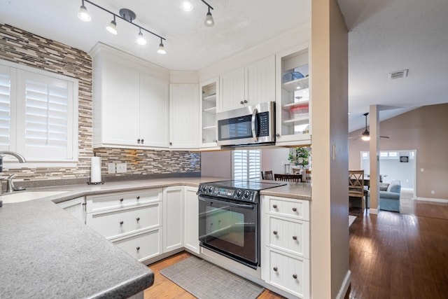 kitchen with backsplash, white cabinets, sink, light hardwood / wood-style flooring, and black / electric stove