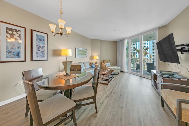 dining room featuring light wood-type flooring, expansive windows, and a notable chandelier