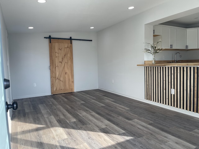 unfurnished room with a barn door, sink, and wood-type flooring