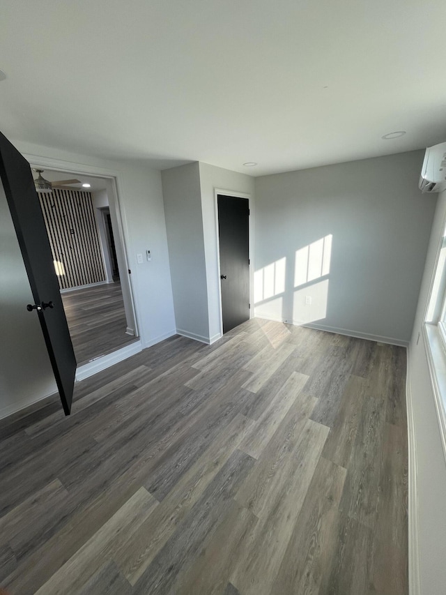 unfurnished room with a wall mounted air conditioner and dark hardwood / wood-style flooring