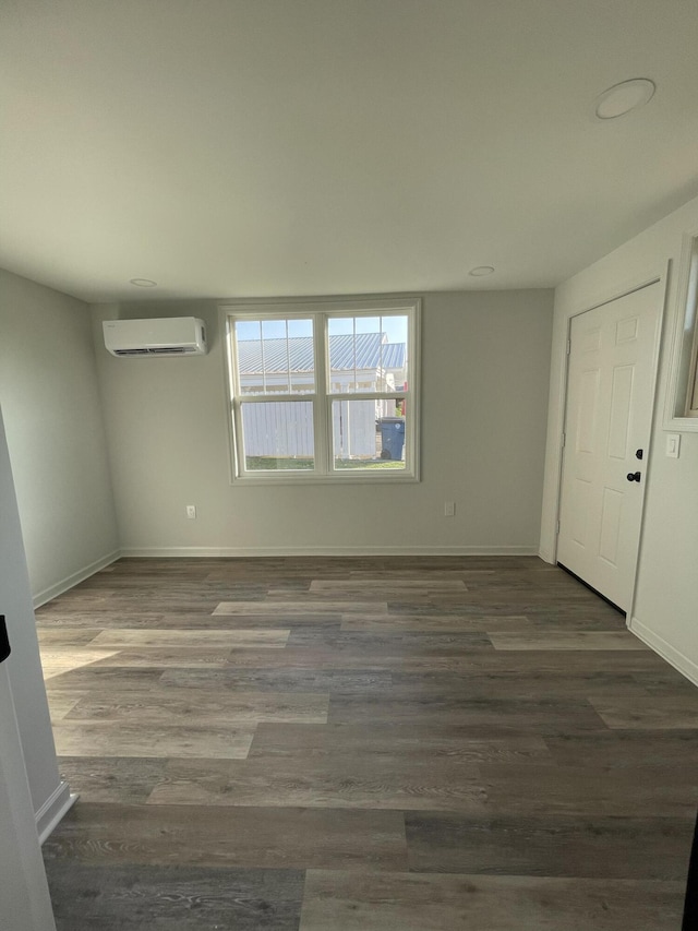 empty room featuring a wall mounted air conditioner and dark hardwood / wood-style floors