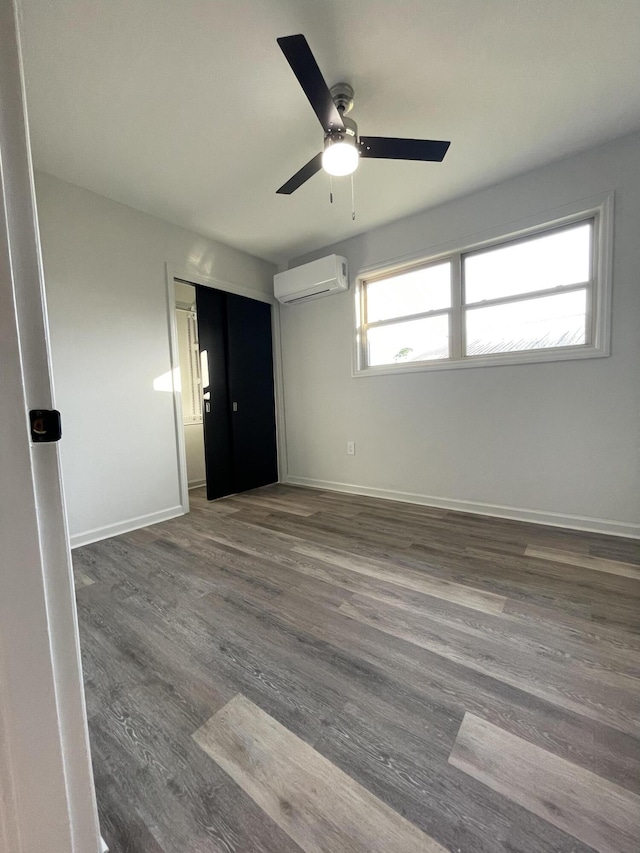 empty room featuring a wall mounted air conditioner, dark hardwood / wood-style floors, and ceiling fan