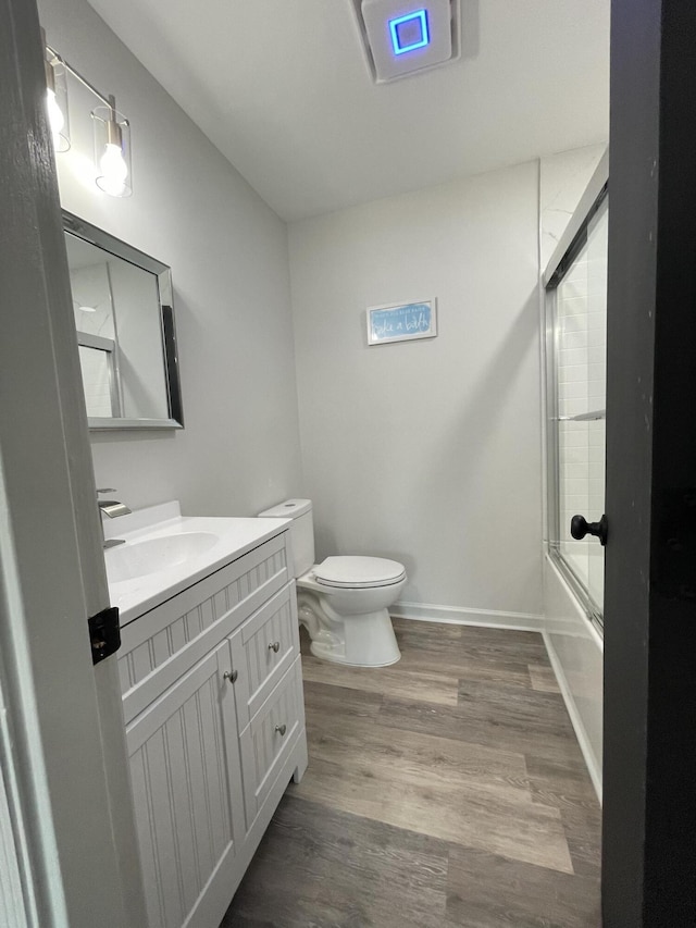 full bathroom with toilet, vanity, enclosed tub / shower combo, and hardwood / wood-style flooring