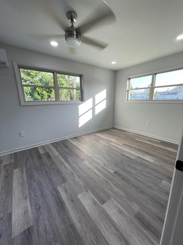 spare room with a wall mounted air conditioner, ceiling fan, and dark wood-type flooring