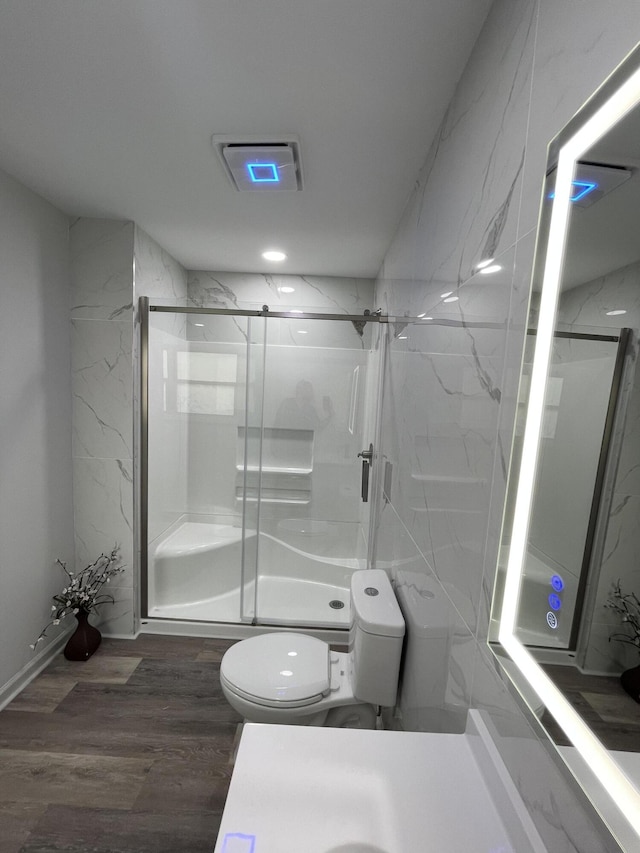 bathroom featuring hardwood / wood-style floors, toilet, walk in shower, and tile walls