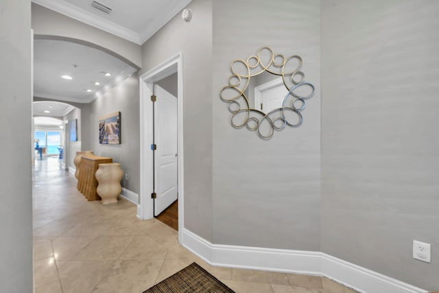 hall with ornamental molding and light tile patterned floors