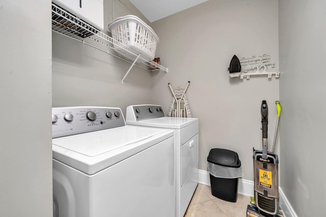 clothes washing area with light tile patterned floors and washer and dryer