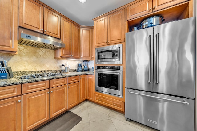 kitchen with dark stone counters, tasteful backsplash, light tile patterned flooring, and stainless steel appliances